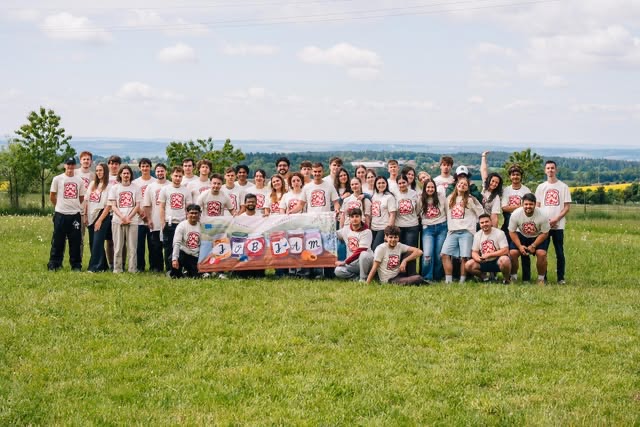 The Job Jam group in matching t-shirts with their banner, on a hill in the Czech countryside